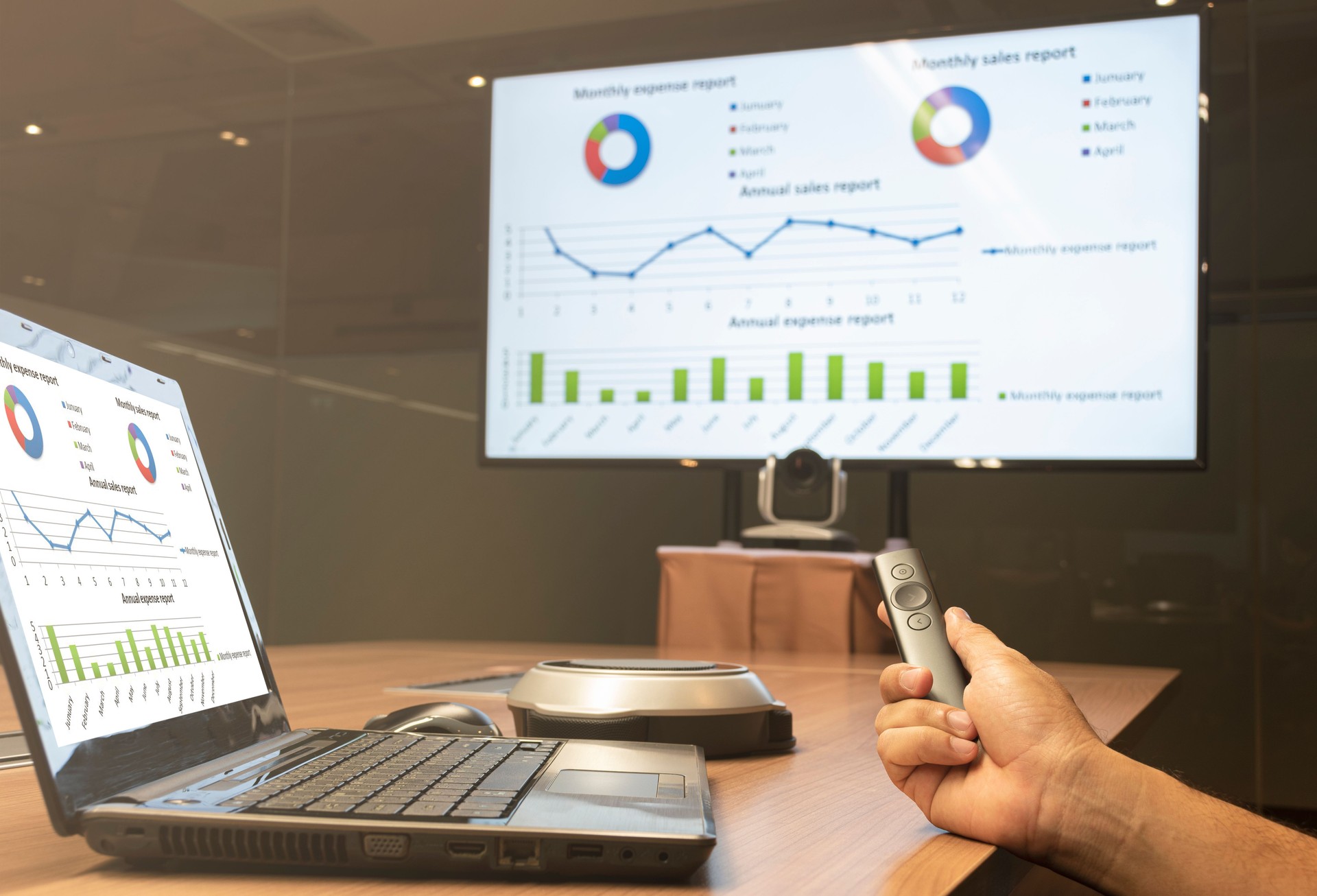 Businessman hand hold remote control slide with presentation on display laptop and television